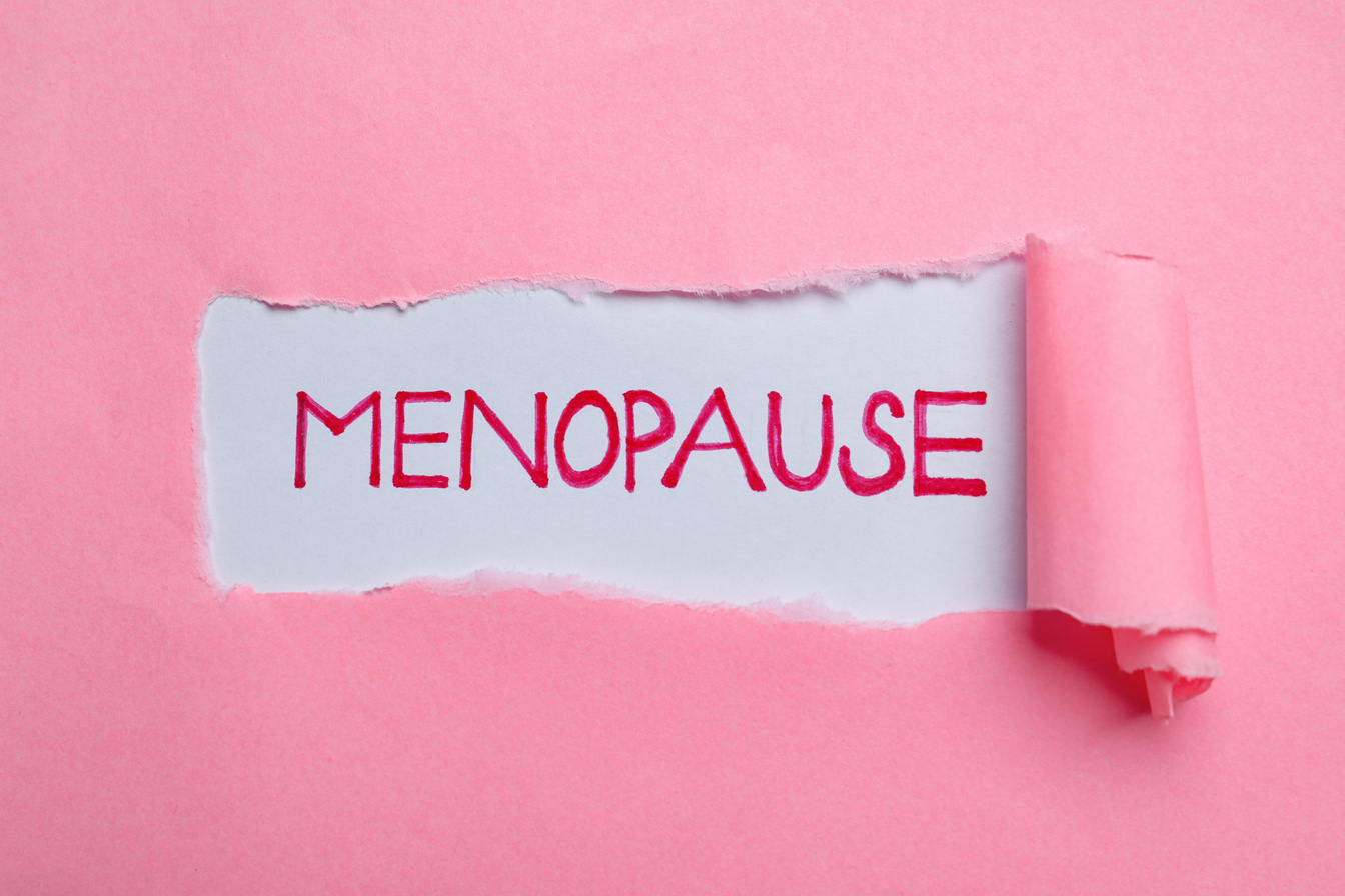 Word Menopause Written on White Background, View through Hole in Pink Paper